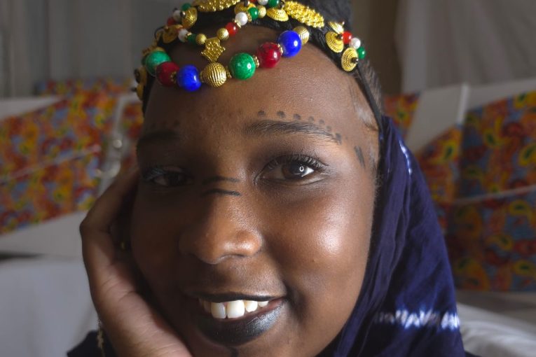 Jeune femme portant un bijou de tête perlé et des motifs traditionnels sur le visage